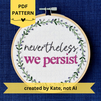 PDF pattern created by Kate, not AI. "Nevertheless, we persist." Nevertheless hand embroidered in a script font in dark gray. "we persist" is in Times New Roman and sewn bright fuchsia embroidery thread. Quote surrounded with a floral wreath with purple and lavender flower buds and green leaves. Stitched on white-on-white cotton. Wall art framed in light wood embroidery hoop.