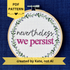PDF pattern created by Kate, not AI. "Nevertheless, we persist." Nevertheless hand embroidered in a script font in dark gray. "we persist" is in Times New Roman and sewn bright fuchsia embroidery thread. Quote surrounded with a floral wreath with purple and lavender flower buds and green leaves. Stitched on white-on-white cotton. Wall art framed in light wood embroidery hoop.