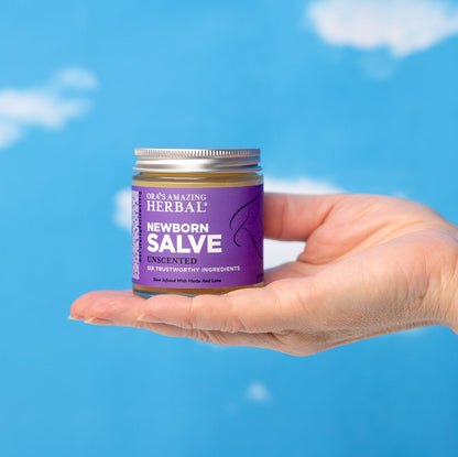 Newborn Salve 4oz Lifestyle Outdoor Human Hand Blue Cloud Background
