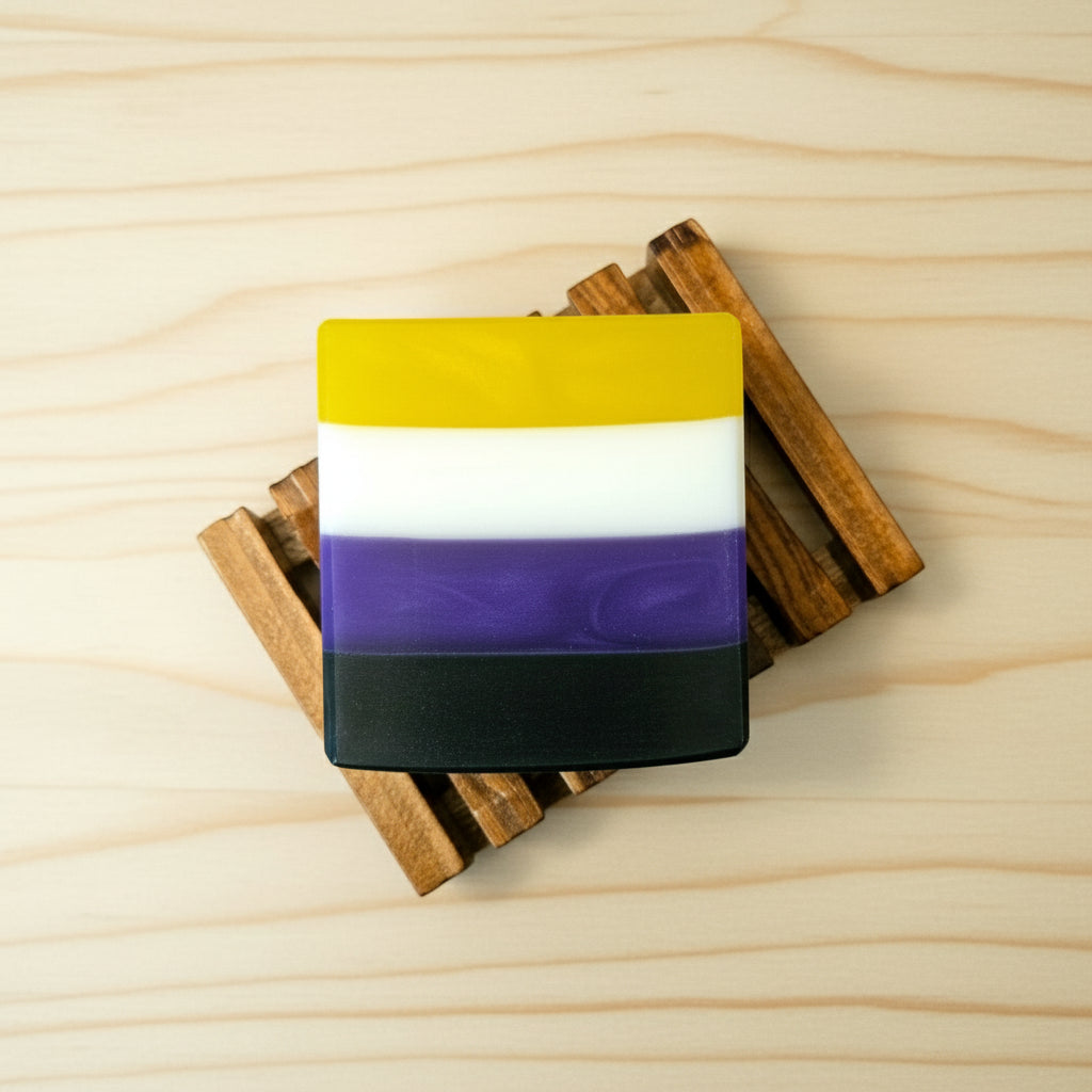 Nonbinary flag colored soap bar sitting on a wooden soap dish
