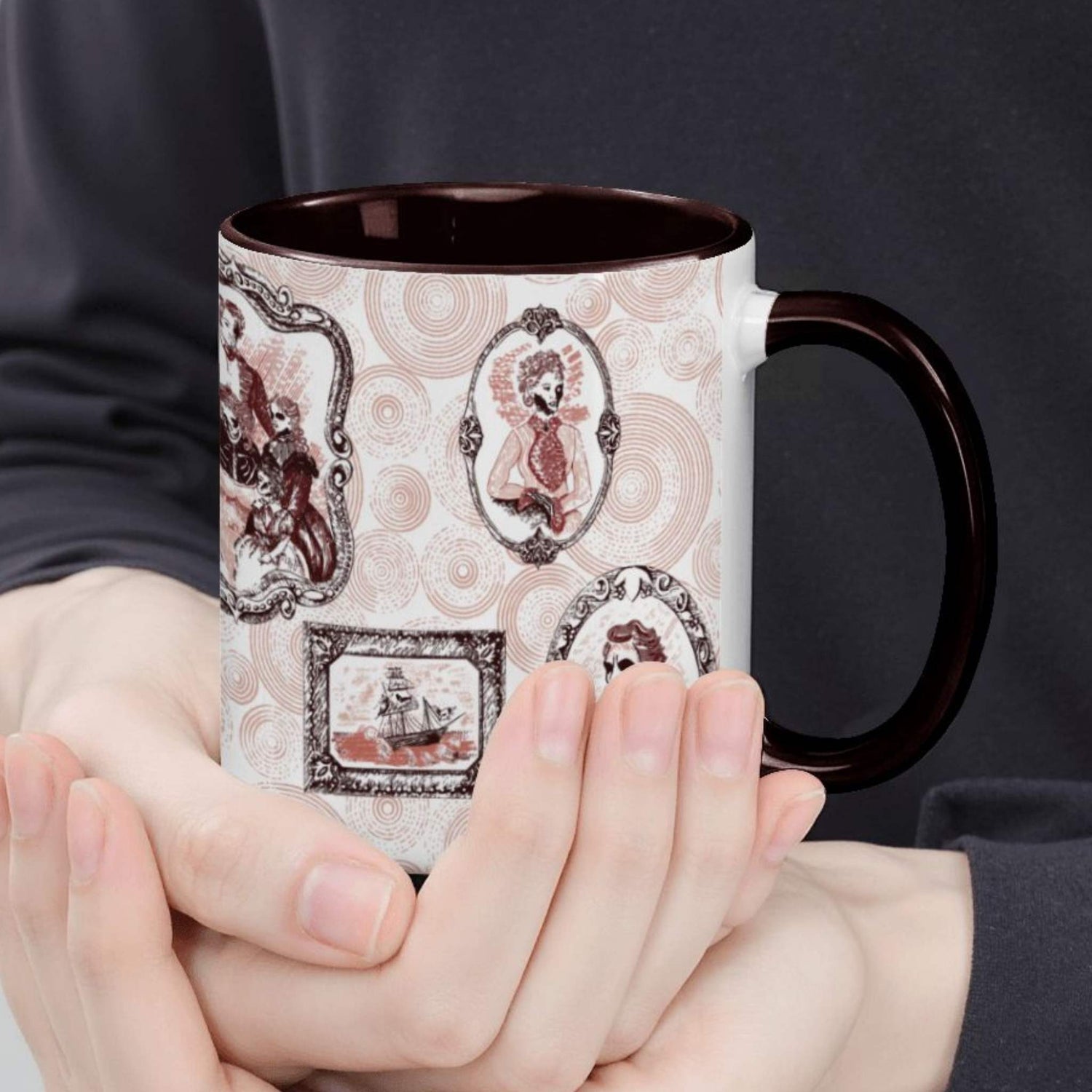 Hands cradling the oxblood portrait mug, close view of red frames holding a skeletal cameo lady and a ribcage gentleman