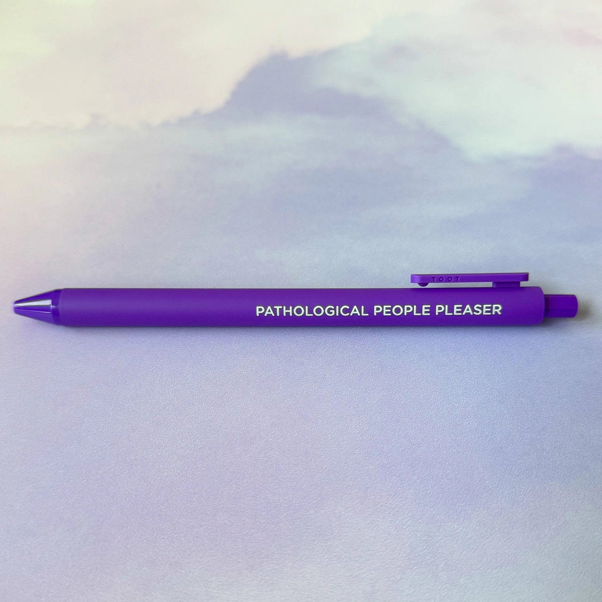 Pathological People Pleaser jotter gel pen flat lay — purple barrel Midnights era desk pen by indie artist MangoIllustrated