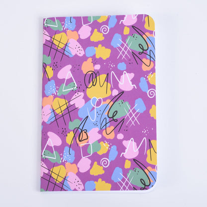 A pocket notebook with a vibrant pink, yellow, green, and blue abstract pattern on a purple background.