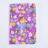 A pocket notebook with a vibrant pink, yellow, green, and blue abstract pattern on a purple background.
