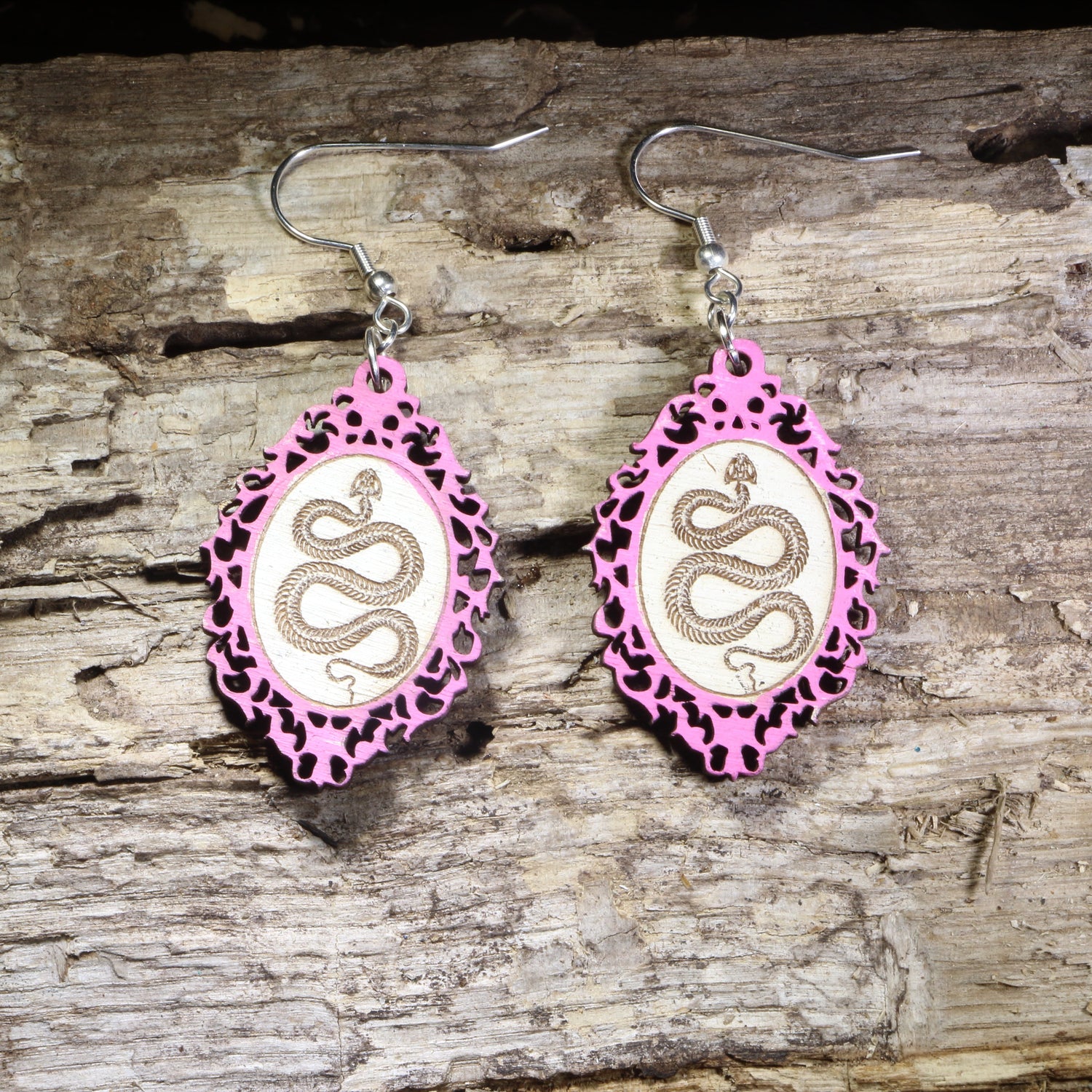 Handcrafted pink framed snake wooden dangle earrings featuring a detailed serpent coiled within an ornate gothic-inspired frame. Lightweight laser-cut wooden earrings with hypoallergenic .925 sterling silver hooks, perfect for snake lovers, gothic fashion, reptile enthusiasts, witchy style, dark academia, and nature-inspired handmade jewelry.