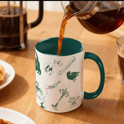Coffee pouring into a forest green preppy skull and bones mug on a wood table beside a French press, green and pink gothic scatter print