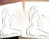 Black and white elegant line art illustration of a sensual woman enjoying her first cup of coffee, head tilted back, in a peaceful pose, titled "But First, Coffee"; black frame on white wainscoting with modern black decor; printed on Aquarelle Rag paper, packaged for shipping.
