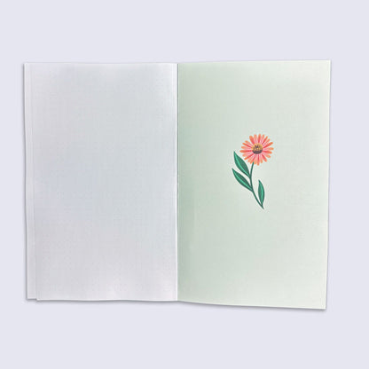Open notebook with a pink flower illustration on a light green page