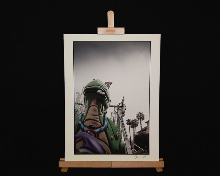 Image of a fine art print of a dragon with a broken tooth on a street carnival ride. 