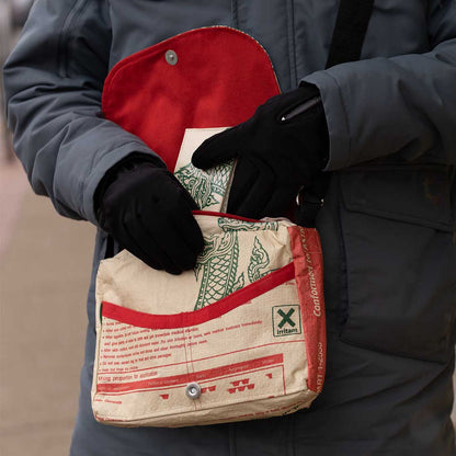 man reaching into small recycled messenger bag