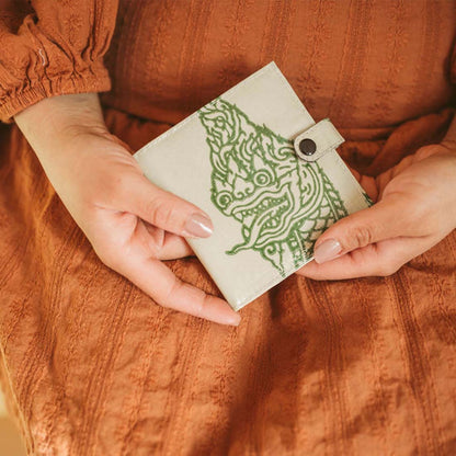 woman holding a small square upcycled wallet with a serpent design