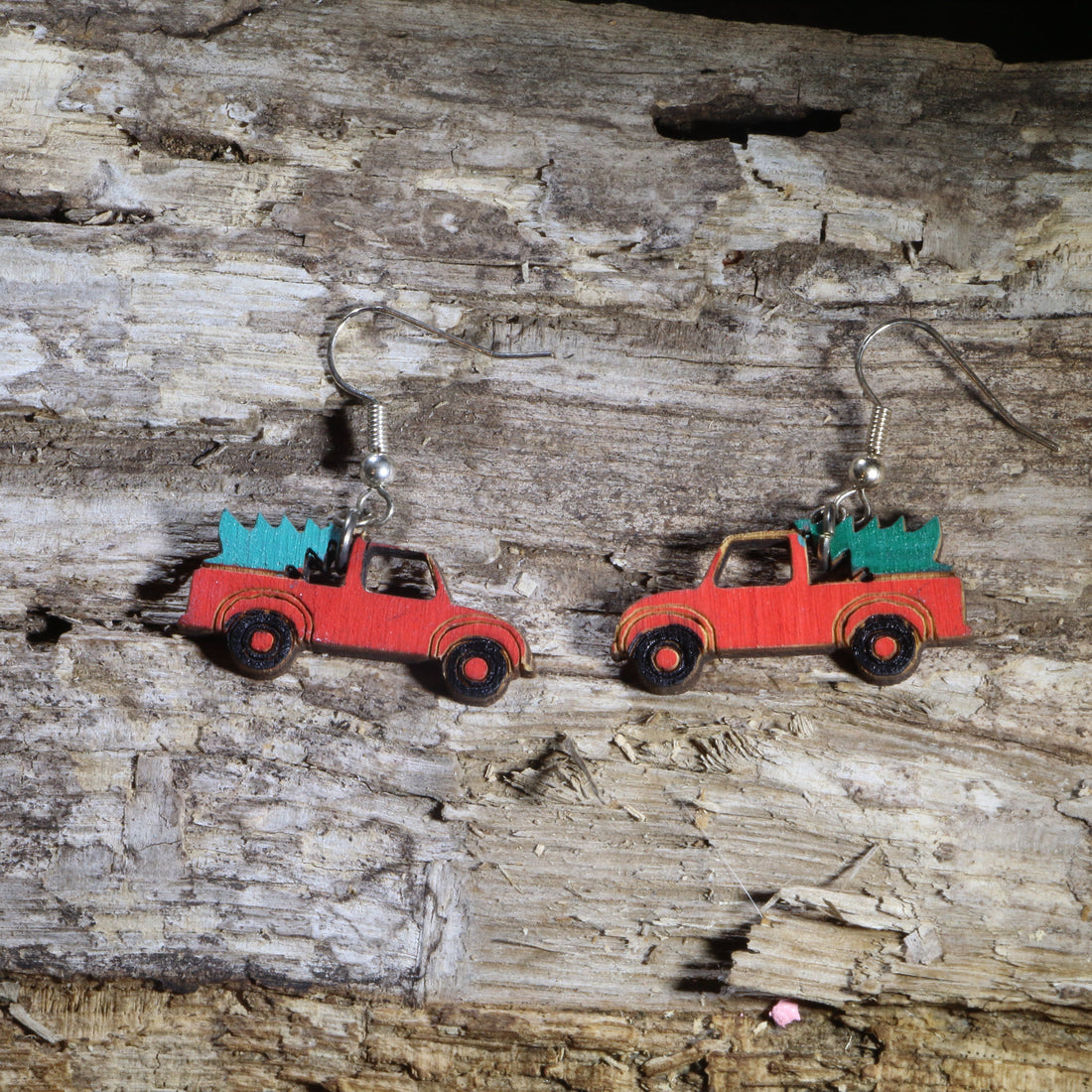 Hand-painted wooden red pickup truck dangle earrings featuring a classic vintage red truck carrying a green Christmas tree in the truck bed. Crafted from lightweight wood with hypoallergenic .925 sterling silver hooks, these festive holiday earrings are perfect for Christmas celebrations, farmhouse décor lovers, country Christmas enthusiasts, winter parties, stocking stuffers, and anyone who loves nostalgic vintage truck Christmas jewelry.