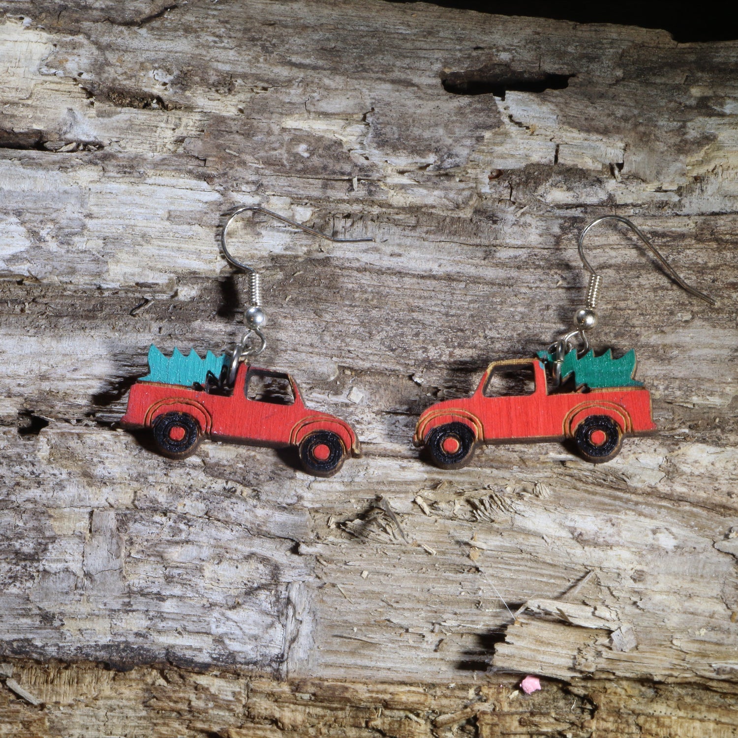 Hand-painted wooden red pickup truck dangle earrings featuring a classic vintage red truck carrying a green Christmas tree in the truck bed. Crafted from lightweight wood with hypoallergenic .925 sterling silver hooks, these festive holiday earrings are perfect for Christmas celebrations, farmhouse décor lovers, country Christmas enthusiasts, winter parties, stocking stuffers, and anyone who loves nostalgic vintage truck Christmas jewelry.