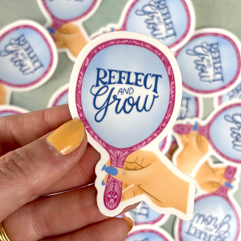 hand holding A sticker with a mirror design and the text &