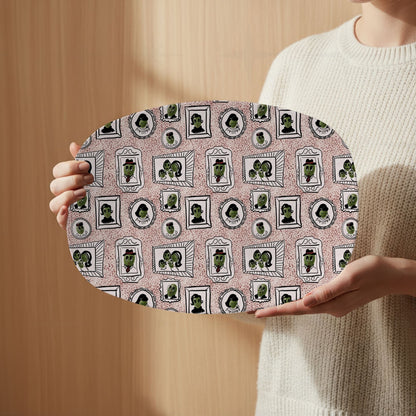 Person in cream sweater holding retro olive portrait serving platter in red speckle colorway face-forward, full mid-century gallery wall framed olive pattern visible against warm wood background