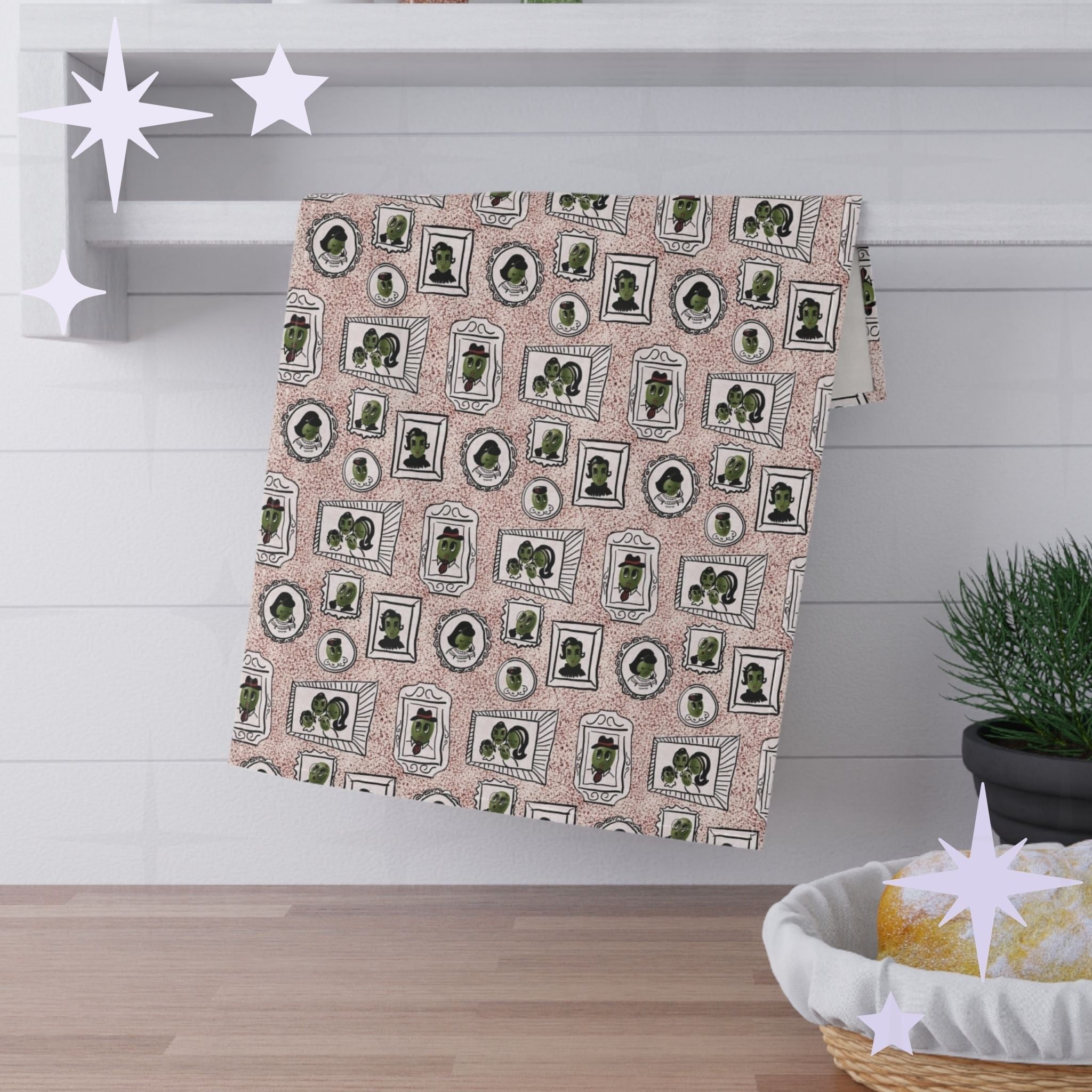Dusty rose retro olive portrait tea towel hanging folded over white kitchen shelf, mid-century illustrated pattern visible, styled with pine sprig