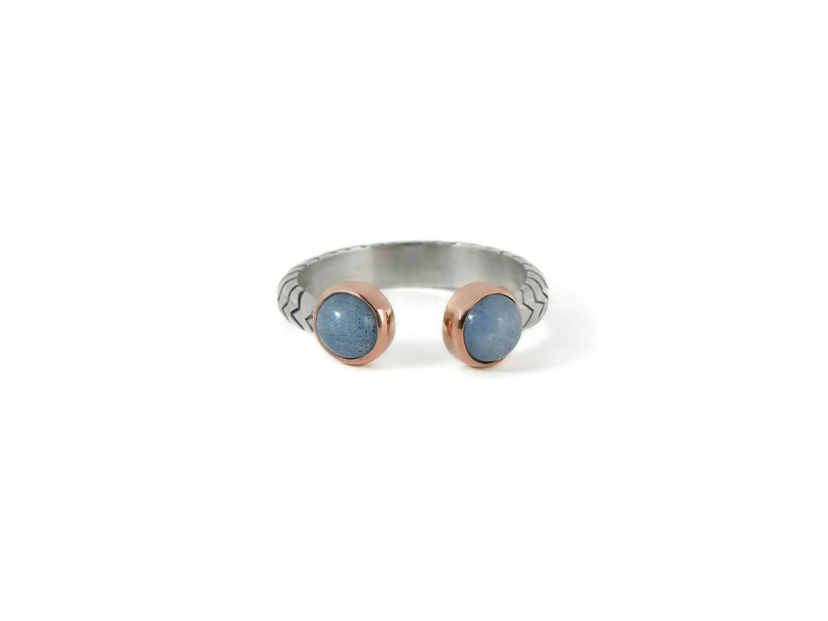 A sterling silver band with diagonal design, and two rose gold bezel set cloudy blue aquamarine stones, ethically made by artisans, flat lay, chicago jewelry online 