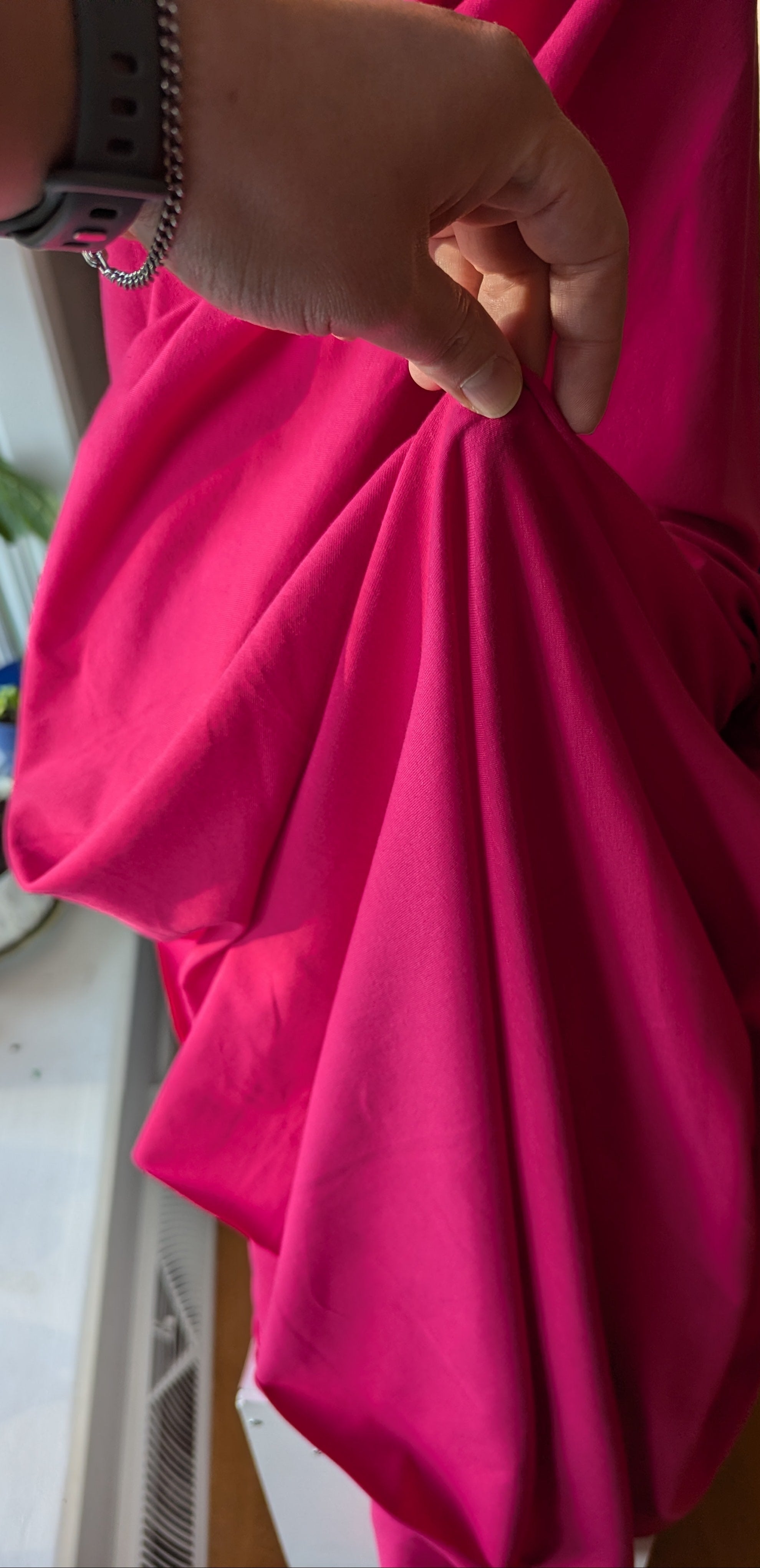 Person holding a bright pink fabric in an indoor setting