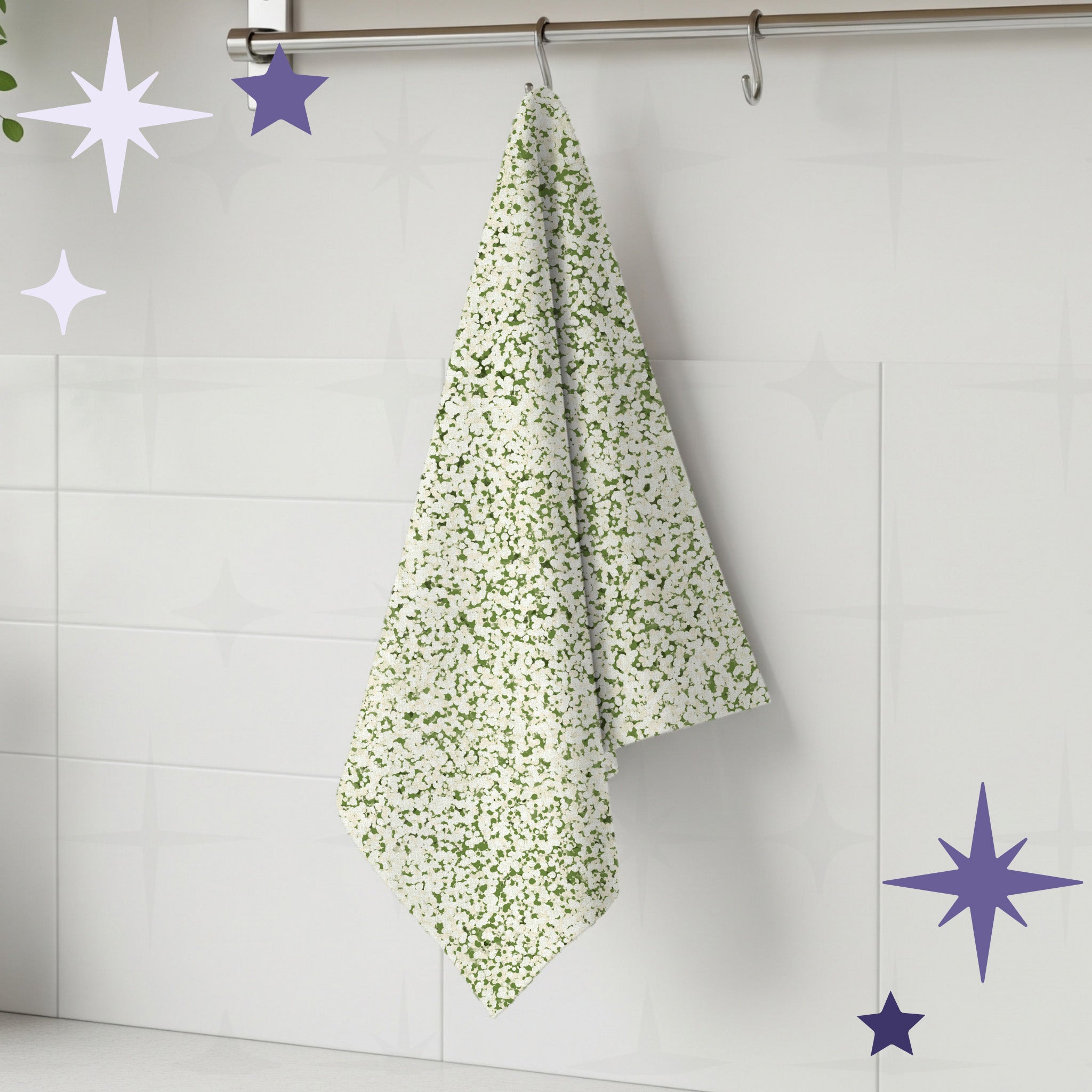 Sage green terrazzo print tea towel hanging from stainless steel rail hook on white tile kitchen wall