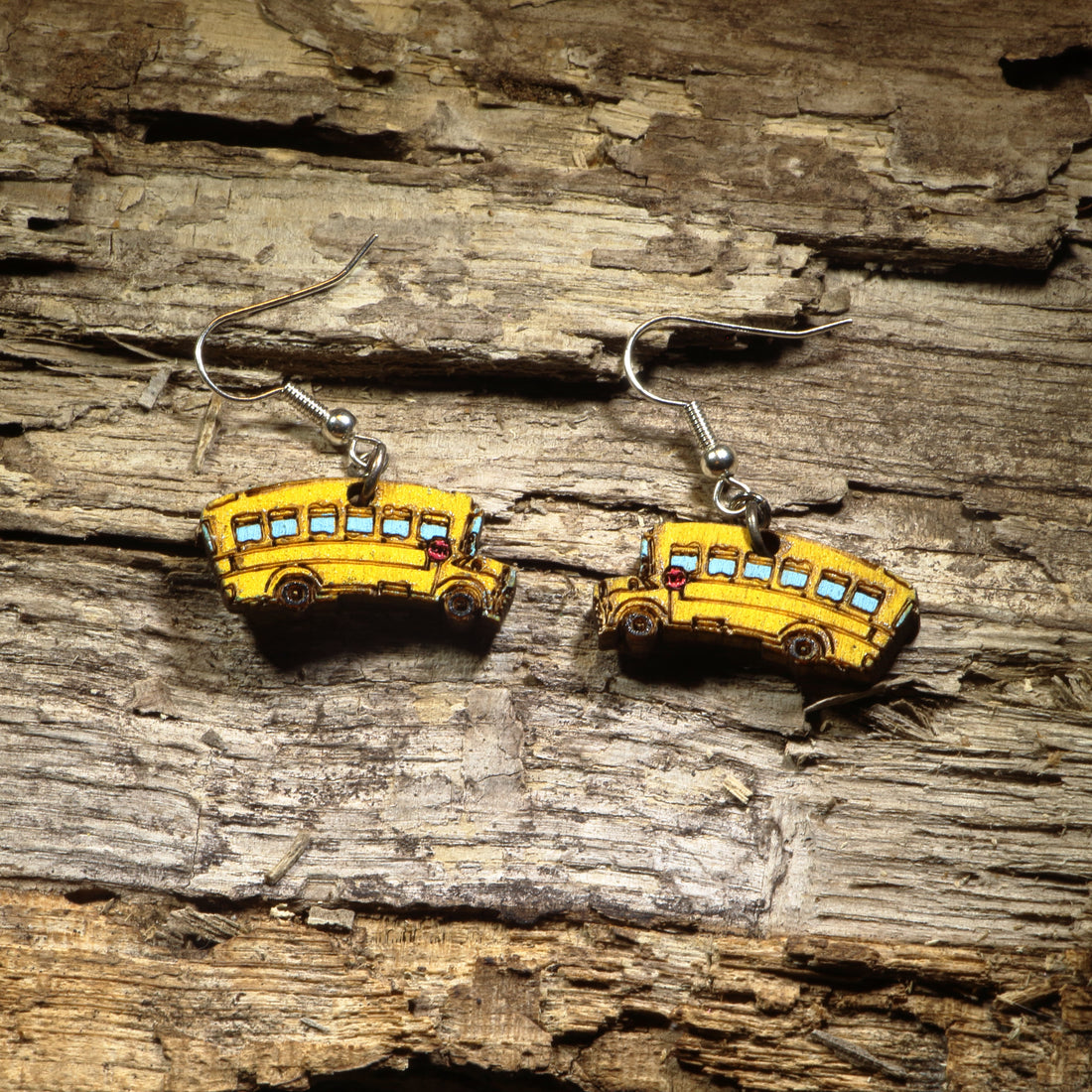 Hand-painted wooden school bus dangle earrings featuring the iconic bright yellow school bus with colorful details. Crafted from lightweight wood with hypoallergenic .925 sterling silver hooks, these charming earrings are perfect for teachers, school bus drivers, educators, students, back-to-school celebrations, and anyone who loves unique school-themed jewelry.