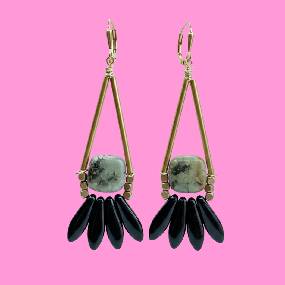 brass, stone and black glass earrings on pink background