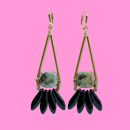 brass, stone and black glass earrings on pink background