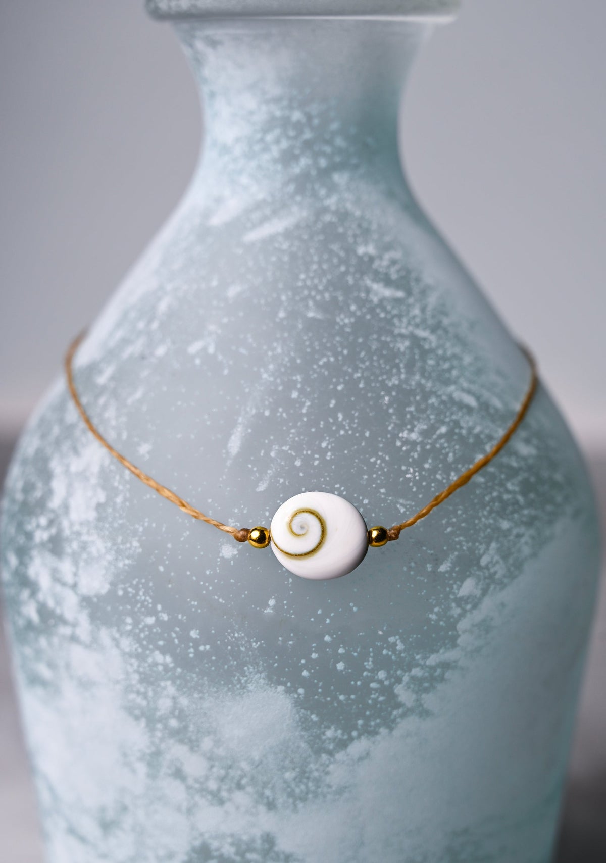A close up view of a shiva eye shell pendant choker necklace.