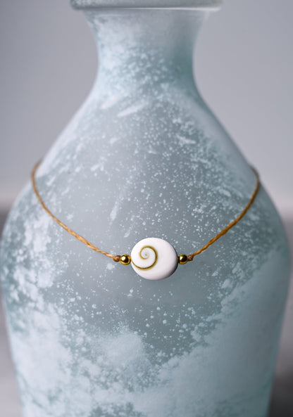 A close up view of a shiva eye shell pendant choker necklace.