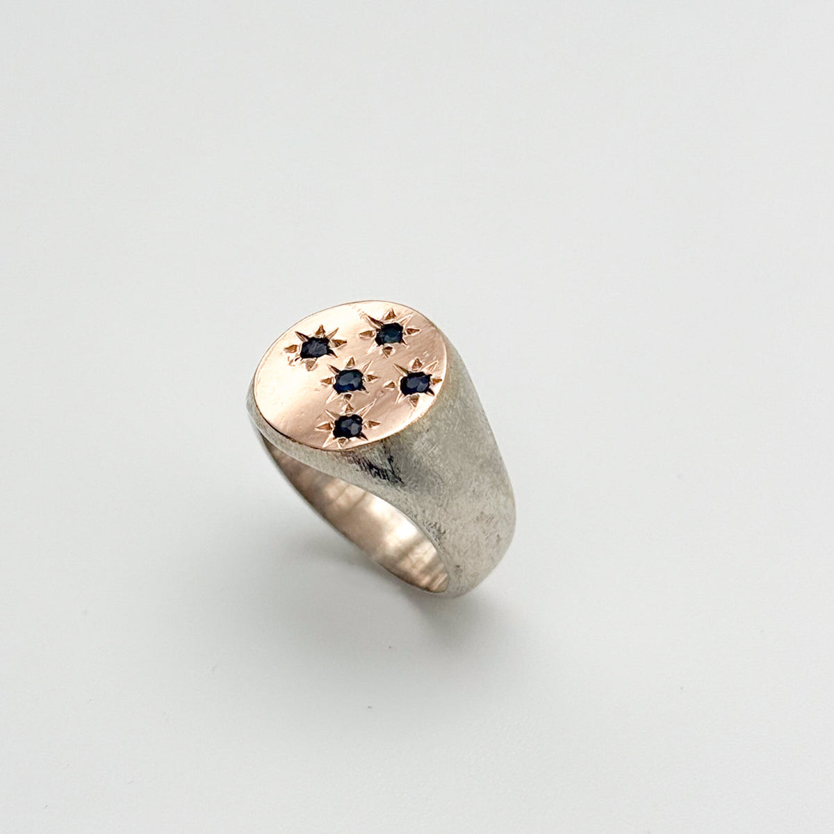 Sterling silver sand blasted ring with rose gold circular signet featuring 5 sapphire stones set in stars, made by hand in mexico, ethical artisan rings in chicago 