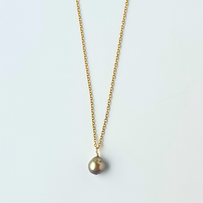 Gold necklace with a single pearl pendant on a light gray background