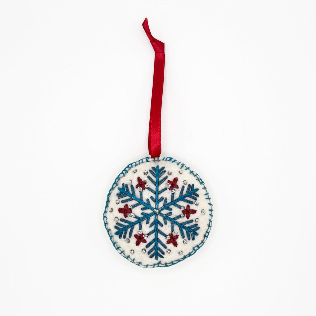 Embroidered by hand, blue red and silver snowflake design on a circular felt ornament strung with a red ribbon, ethically made by hand