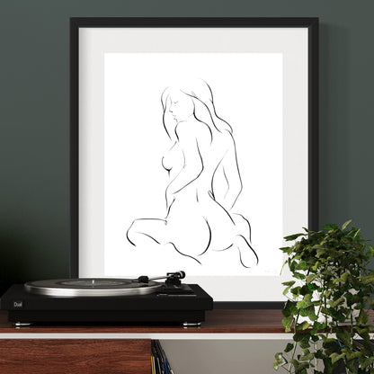 Black and white elegant illustration of sensual woman in seated pose with feminine curves; matted in black frame above oak desk and record player
