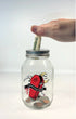 A clear glass mason jar with a silver metal lid, featuring a gothic coffin graphic, with dripping blood, moon, scythe, bats, pentagram, spider, and a moon with the text &