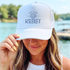 A woman wearing a white trucker hat with &