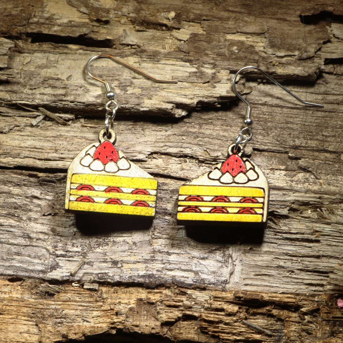 Hand-painted wooden strawberry shortcake dangle earrings featuring delicious layered strawberry cake slices topped with whipped cream and a bright red strawberry. Crafted from lightweight wood with hypoallergenic .925 sterling silver hooks, these sweet dessert earrings are perfect for bakers, pastry lovers, foodies, strawberry fans, and anyone who enjoys fun food-inspired jewelry with a whimsical touch.