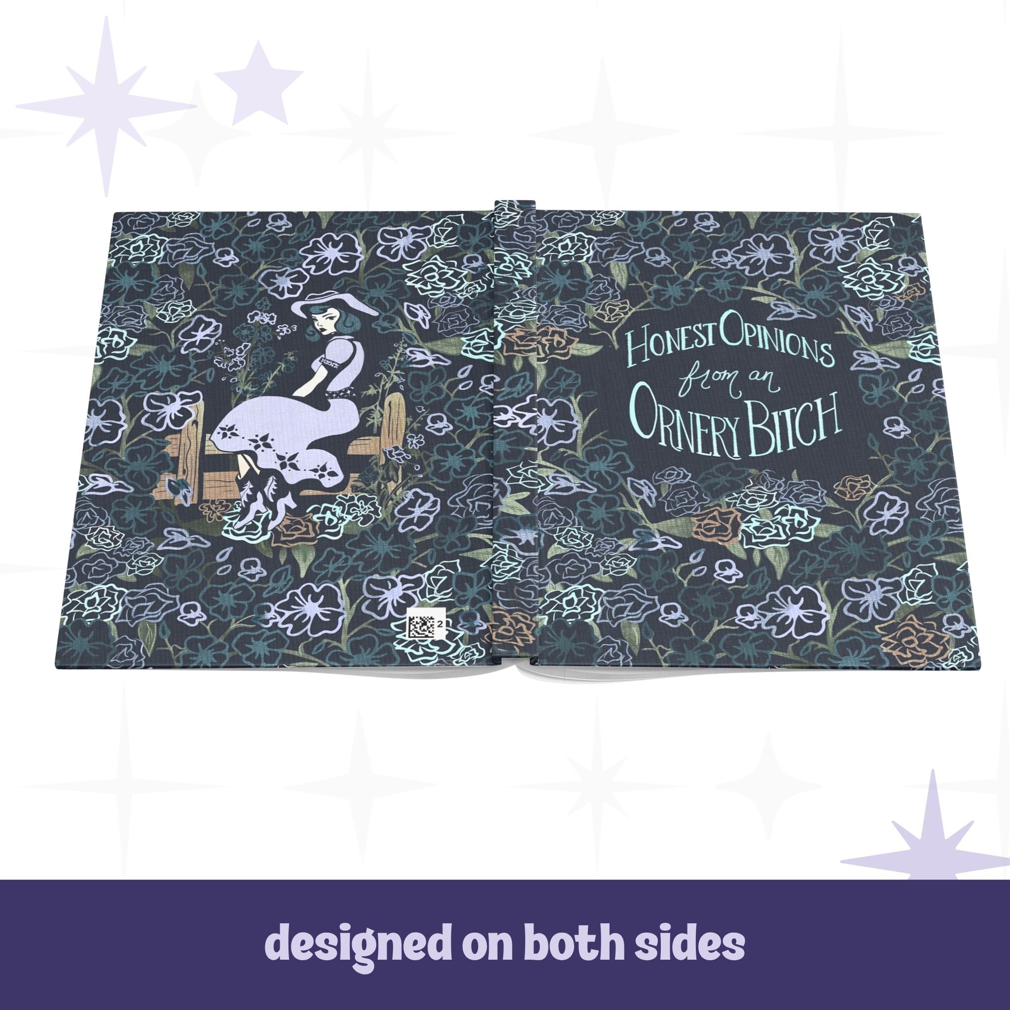 Ornery Bitch hardcover journal open flat showing full wrap design with cowgirl pinup illustration on back cover and hand-lettered text on front, dark floral pattern across both sides