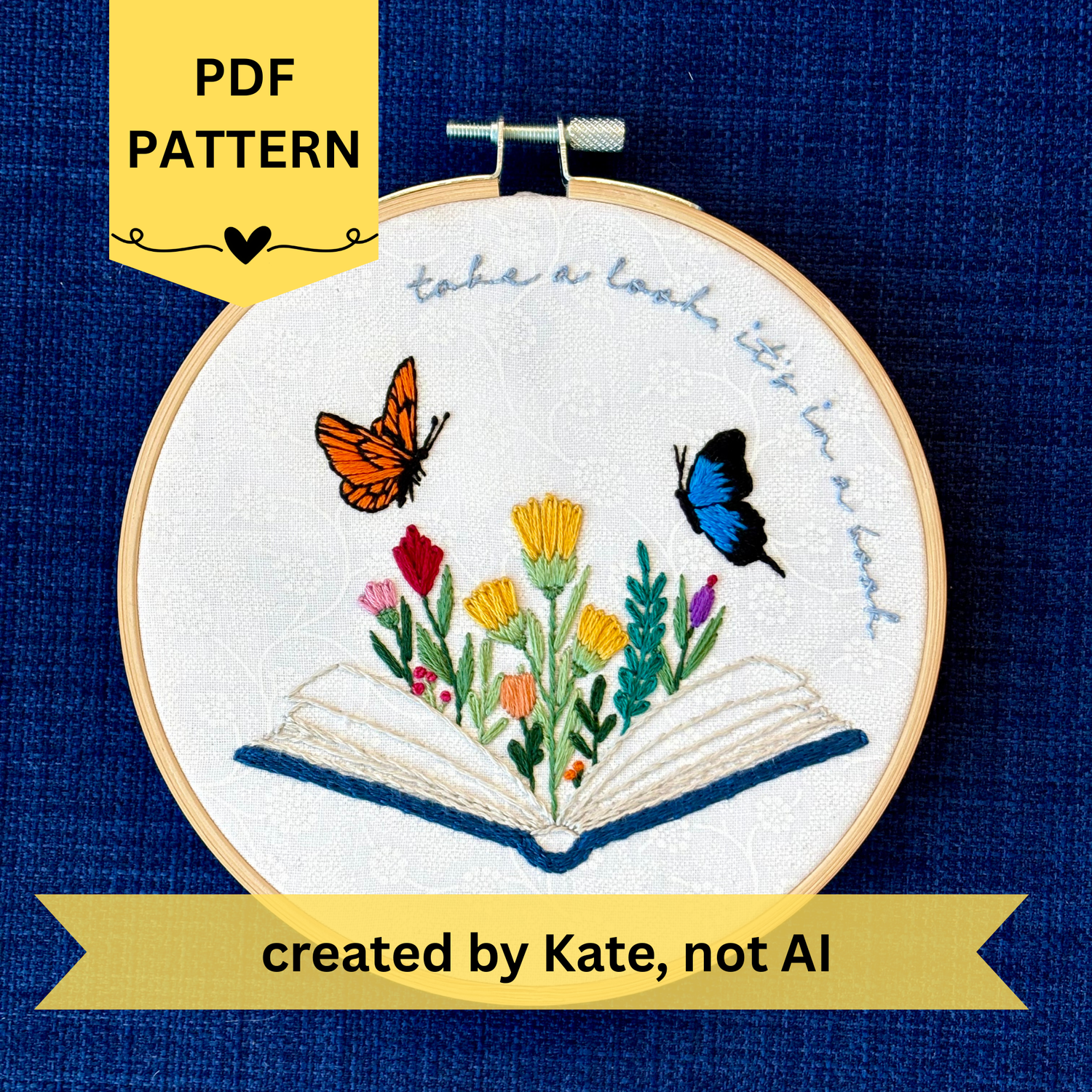 PDF pattern created by Kate, not AI. Photo of a hand embroidered design inspired by Reading Rainbow. Fabric is white cotton with white flowers printed on it. There is an open book with a rainbow of flowers growing from it. Hovering above are an orange and black butterfly and a bright blue and black butterfly. The top right curve of the pattern reads, "take a look, it&
