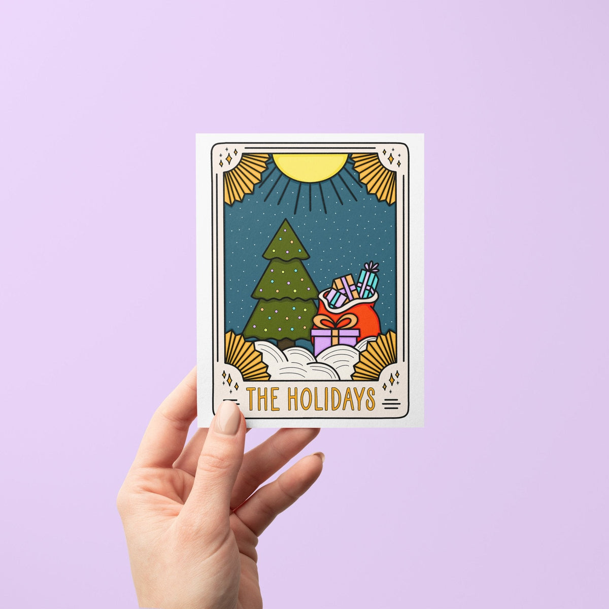 The Holiday Tarot Card Christmas card detail — tarot Christmas card held to show its A2 size by indie artist MangoIllustrated