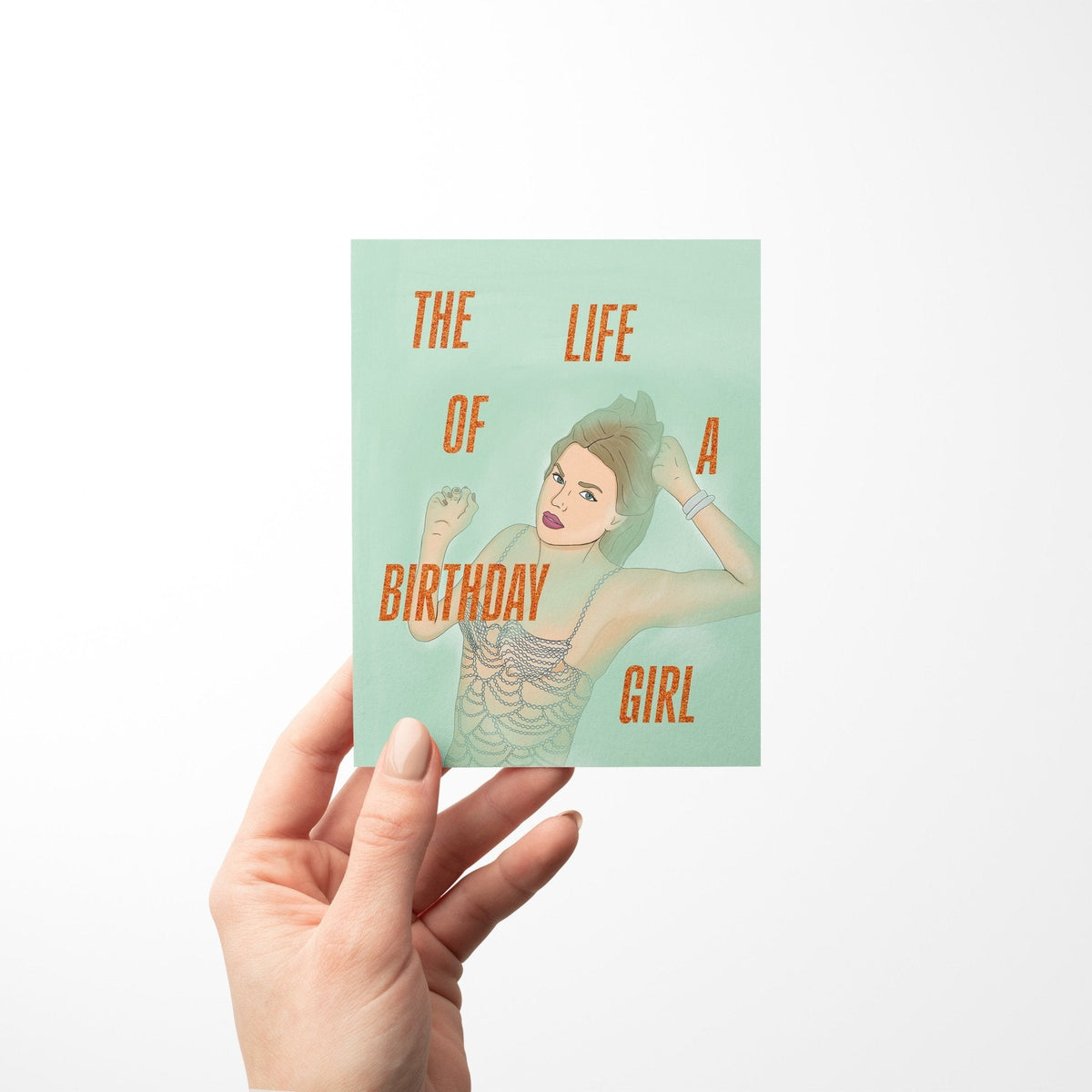 The Life of a Birthday Girl card in hand — showgirl birthday card held to show its A2 size by indie artist MangoIllustrated