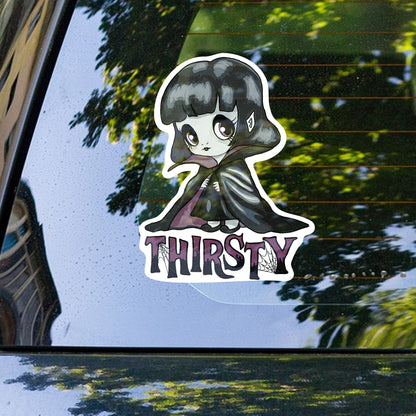 Creepy cute vampire girl sticker on a car rear window with trees reflected behind