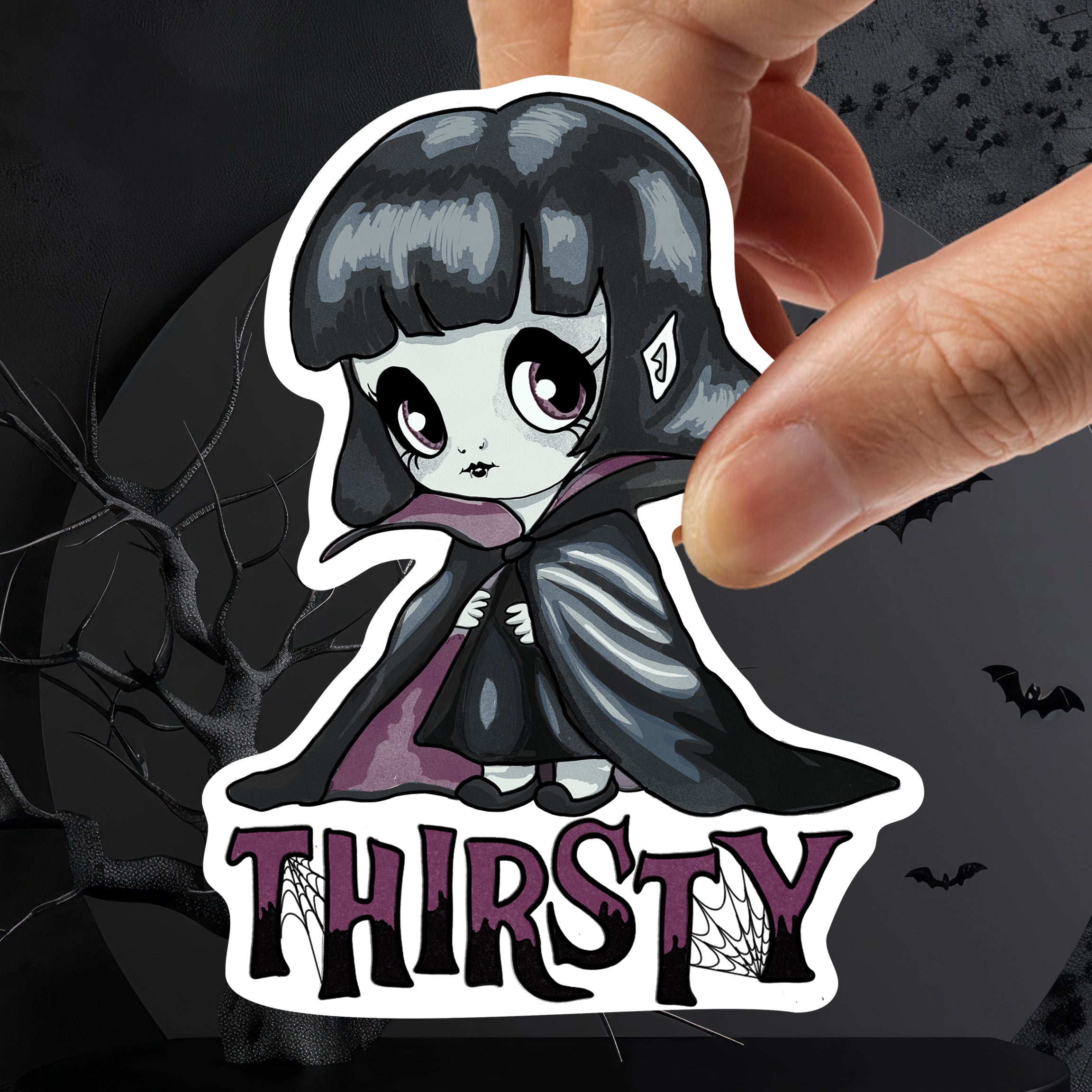 Chibi vampire girl sticker with plum eyes and black cloak held in fingers above webbed THIRSTY lettering
