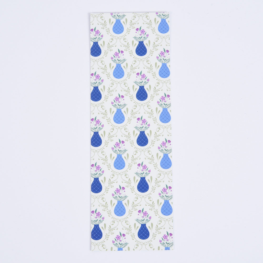 A bookmark with a floral pattern featuring blue flower vases on a light sage green background