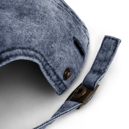 Close-up of faded blue cotton dad hat strap with brass buckle and distressed fabric detail on white background