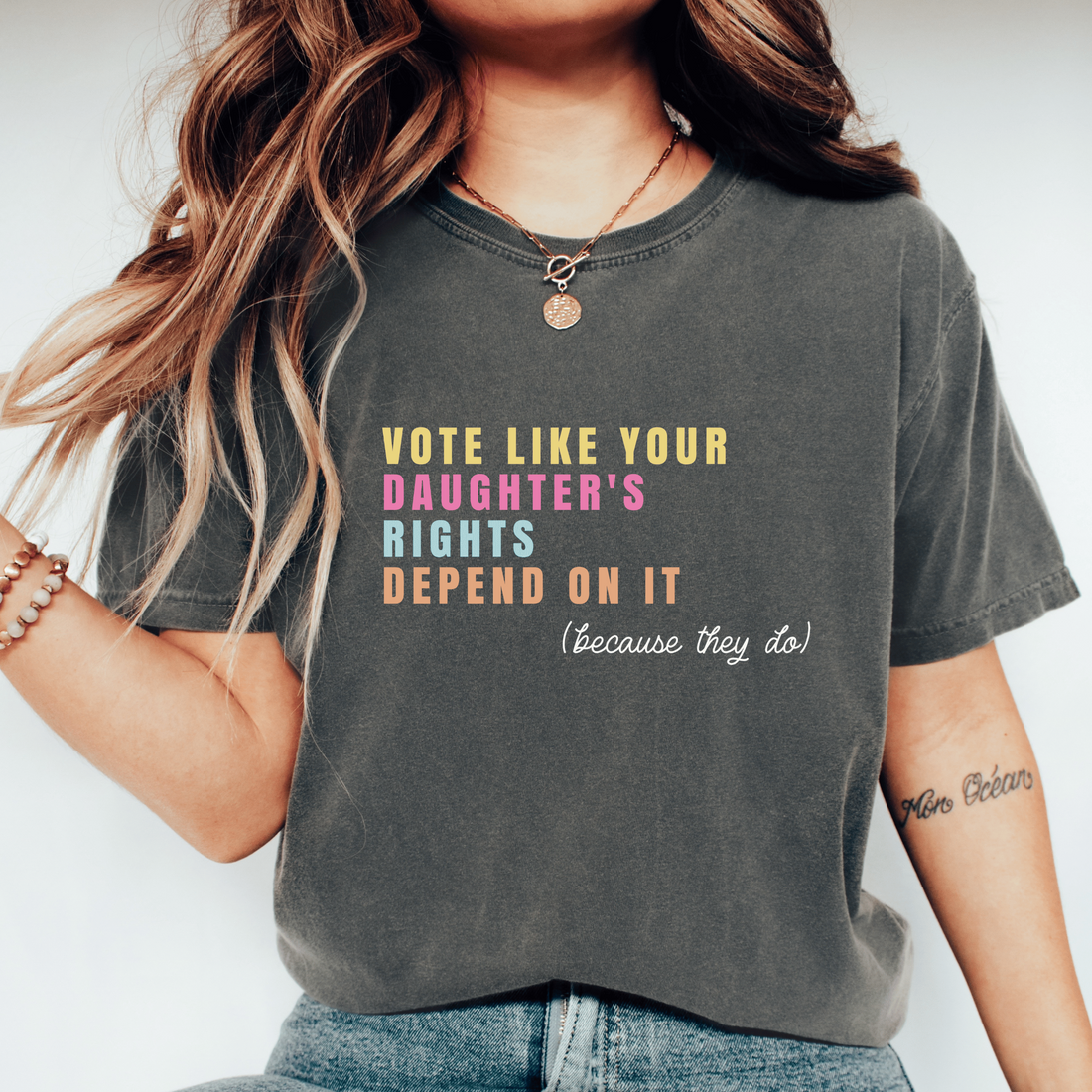 A woman wearing a dark gray graphic t-shirt with the text &