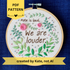 PDF pattern created by Kate, not AI. "Hate is loud. We are louder." Pride quote hand embroidered in chocolate brown. Surrounded by green leaves & vines, with pink roses, blue berries, & metallic silver dots. Sewn on white-on-white cotton. Framed in light wood embroidery hoop as wall art.