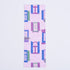 A bookmark featuring a pattern of whimsical city scenes with windows, flower boxes, and a cat on a pink brick backdrop.