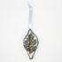 Hand embroidered and sewn oblong Christmas ornament with a brown branch, greenery and blue berries, ethically made by syrian refugee women, lay flat