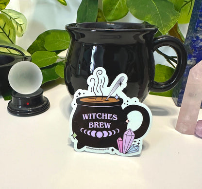 A die-cut sticker featuring a black cauldron with the words &
