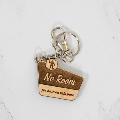 Walnut wood keychain shaped like a trail marker sign, engraved No Room For Hate On This Path with a Bigfoot silhouette, handmade by PRWMade