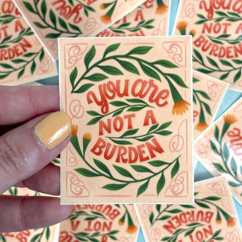 hand holding A sticker with a floral pattern and the text &